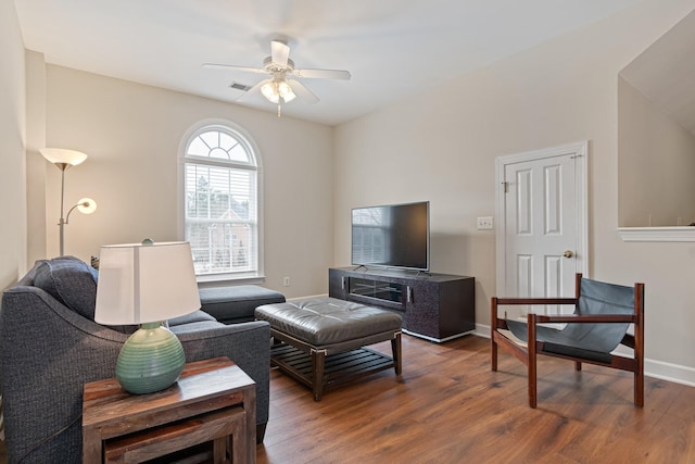 living area featuring a ceiling fan, visible vents, baseboards, and wood finished floors