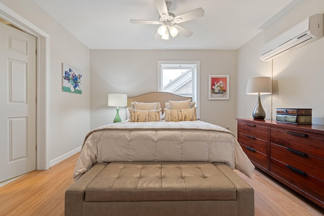 bedroom featuring ceiling fan, light wood finished floors, a wall mounted air conditioner, and baseboards