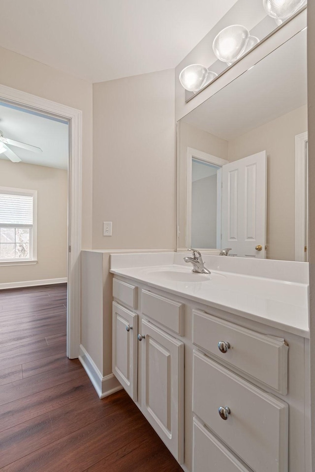 bathroom with a ceiling fan, baseboards, wood finished floors, and vanity