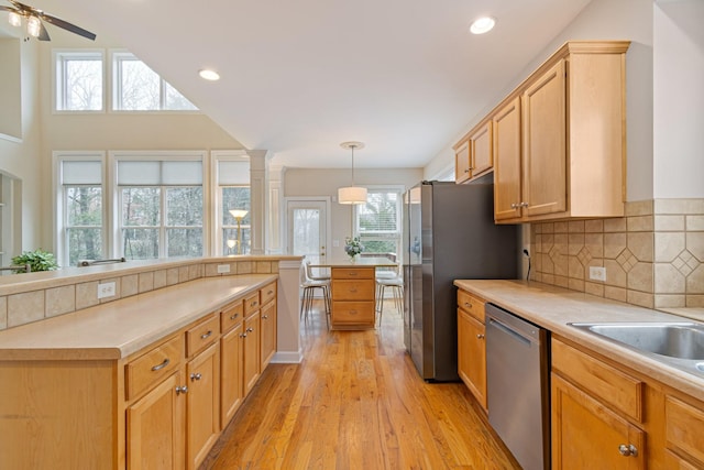 kitchen with light wood finished floors, decorative backsplash, appliances with stainless steel finishes, light countertops, and recessed lighting