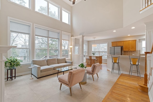 living room featuring recessed lighting, baseboards, and ornate columns