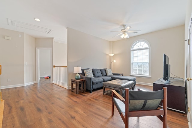 living area with attic access, ceiling fan, baseboards, and wood finished floors