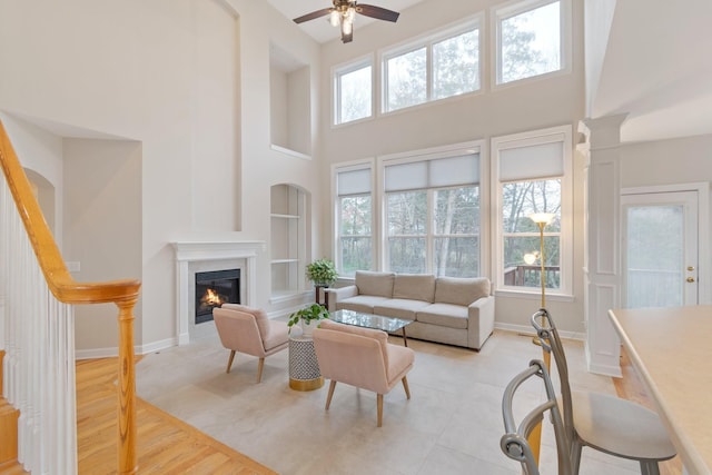 living area with a glass covered fireplace, a healthy amount of sunlight, and baseboards