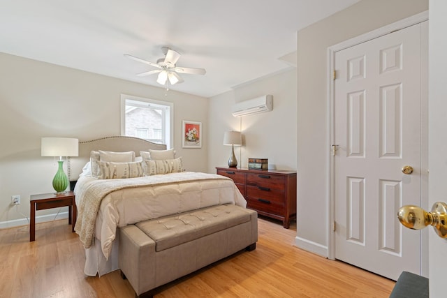 bedroom with light wood-style flooring, baseboards, ceiling fan, and an AC wall unit