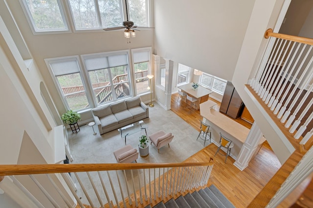 living room with a high ceiling, stairway, wood finished floors, and ornate columns