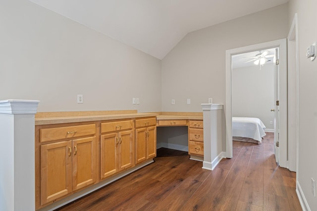 unfurnished office featuring lofted ceiling, dark wood-type flooring, built in study area, and baseboards