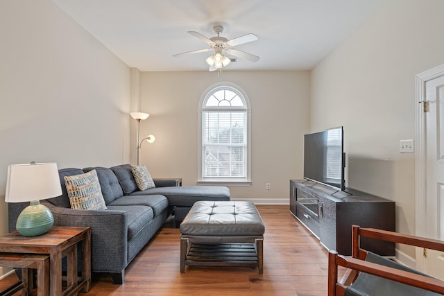 living room with a ceiling fan, baseboards, and wood finished floors