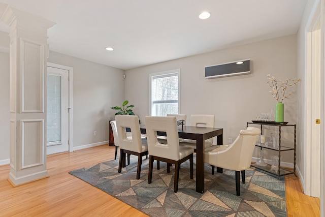 dining room with decorative columns, recessed lighting, light wood-style flooring, an AC wall unit, and baseboards