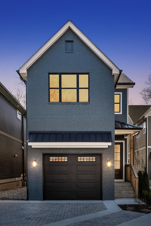 view of front of home with metal roof, an attached garage, brick siding, decorative driveway, and a standing seam roof