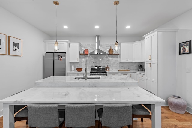 kitchen featuring appliances with stainless steel finishes, white cabinets, wall chimney range hood, and tasteful backsplash