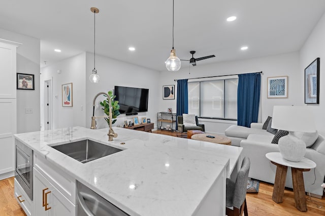 kitchen featuring light wood-type flooring, appliances with stainless steel finishes, open floor plan, and a sink