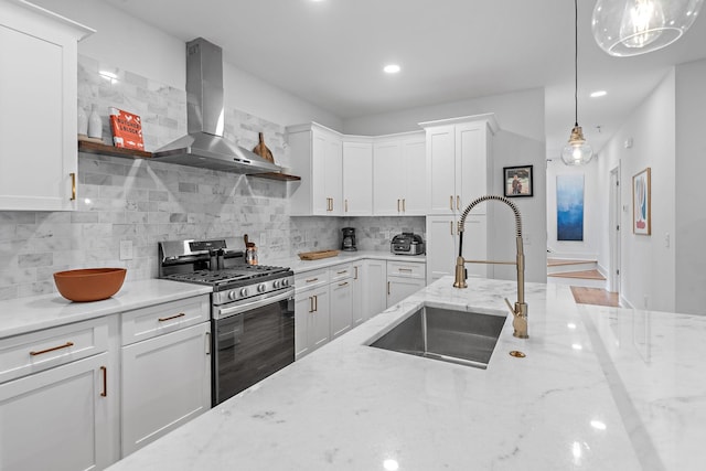 kitchen with decorative backsplash, white cabinets, a sink, ventilation hood, and stainless steel gas range oven