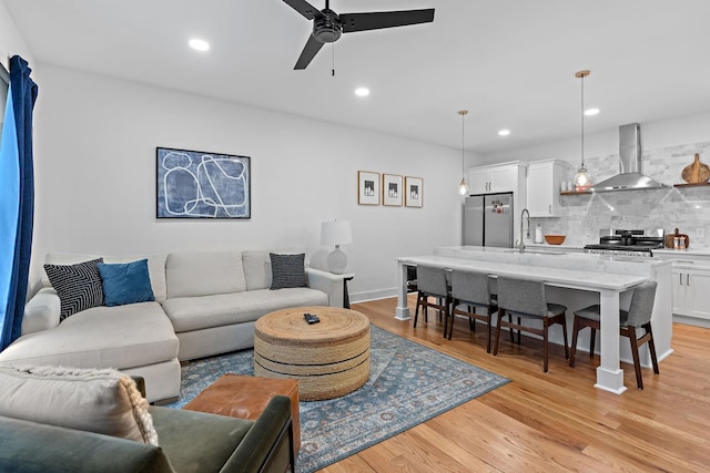 living room featuring ceiling fan, light wood finished floors, and recessed lighting