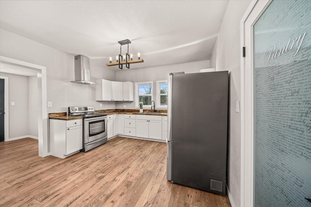 kitchen featuring white cabinets, appliances with stainless steel finishes, range hood, light wood-style floors, and a sink