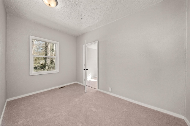 spare room with carpet floors, baseboards, visible vents, and a textured ceiling