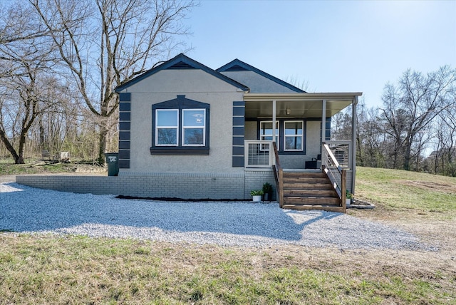 view of front of house featuring covered porch, brick siding, and stucco siding