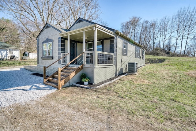 bungalow with a porch, gravel driveway, central air condition unit, a front lawn, and stucco siding