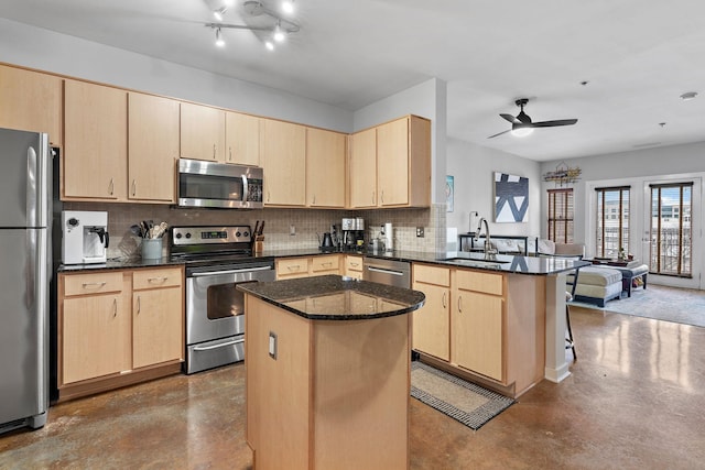 kitchen with stainless steel appliances, light brown cabinets, a sink, and a peninsula