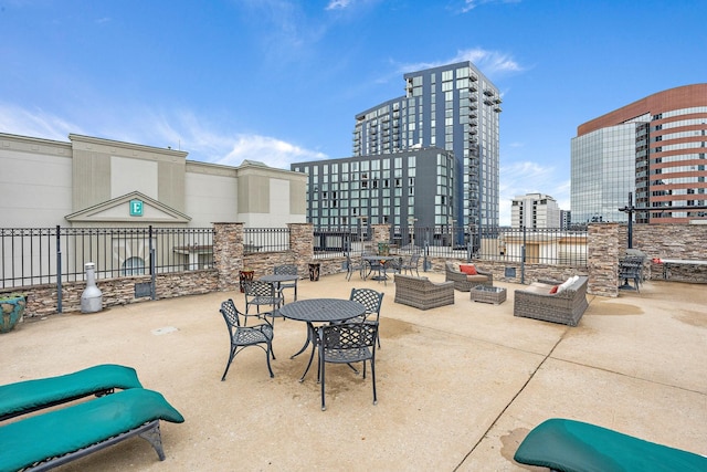 view of patio with a city view, fence, and outdoor lounge area