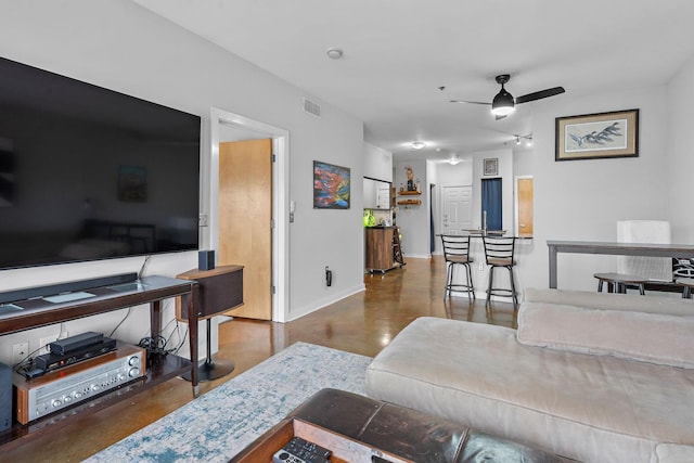 living area featuring baseboards, a ceiling fan, visible vents, and finished concrete floors