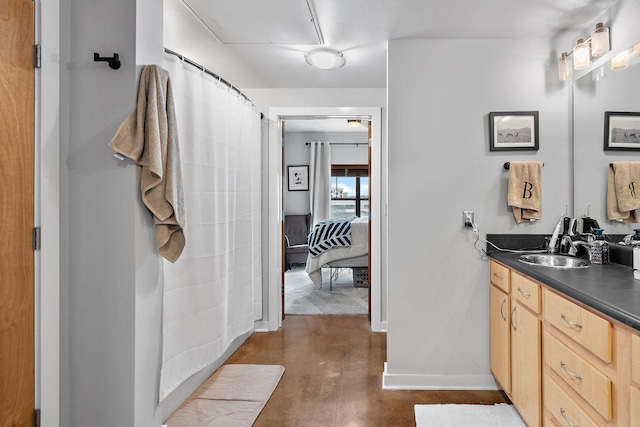 ensuite bathroom with concrete flooring, connected bathroom, vanity, baseboards, and a shower with curtain