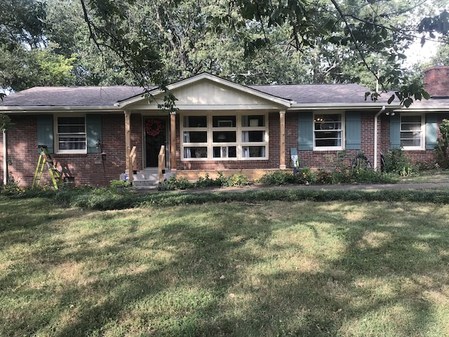 single story home with a front yard, a chimney, and brick siding