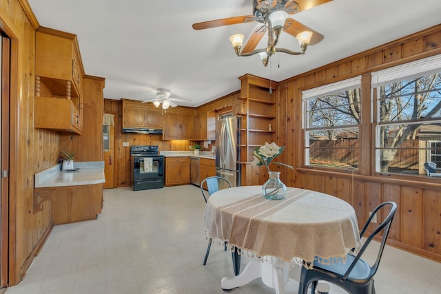 dining room featuring a ceiling fan, wood walls, and light floors