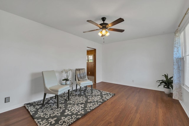 living area featuring a ceiling fan, baseboards, and wood finished floors