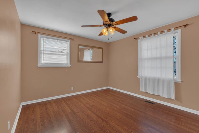 unfurnished room featuring a ceiling fan, visible vents, baseboards, and wood finished floors