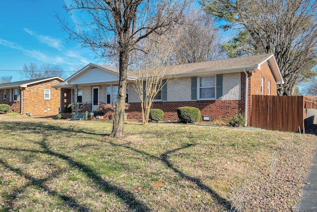 ranch-style home with covered porch, brick siding, a shingled roof, fence, and a front yard