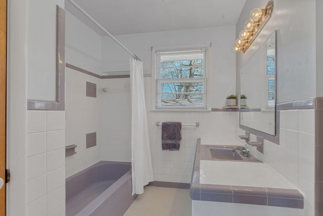 full bathroom with a wainscoted wall, shower / bath combo with shower curtain, tile walls, and vanity