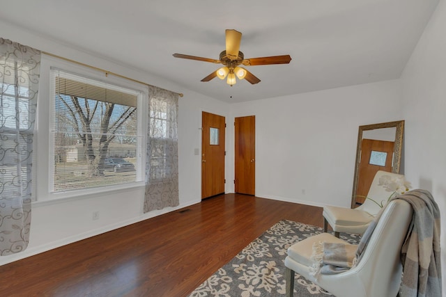 living area featuring visible vents, wood finished floors, a ceiling fan, and baseboards