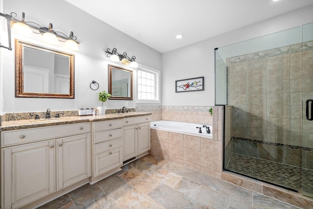 bathroom with double vanity, stone finish floor, a garden tub, a shower stall, and a sink