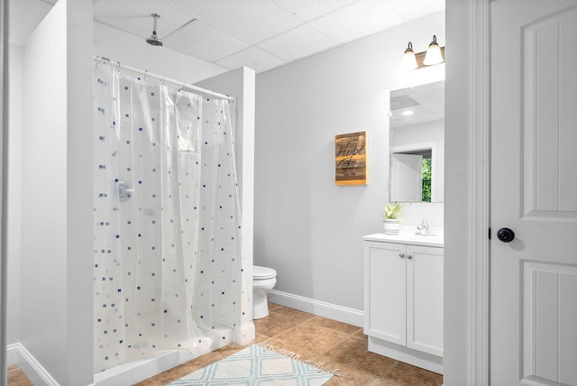 bathroom featuring toilet, a stall shower, a paneled ceiling, and vanity