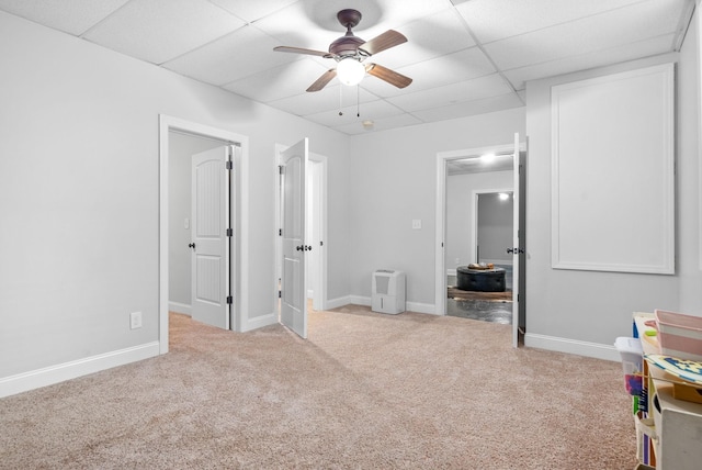 unfurnished bedroom featuring carpet, baseboards, ceiling fan, and a drop ceiling