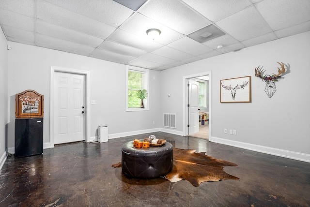 interior space featuring a paneled ceiling, baseboards, finished concrete flooring, and visible vents