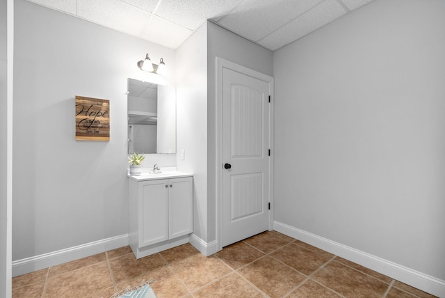 bathroom featuring a drop ceiling, vanity, baseboards, and tile patterned floors