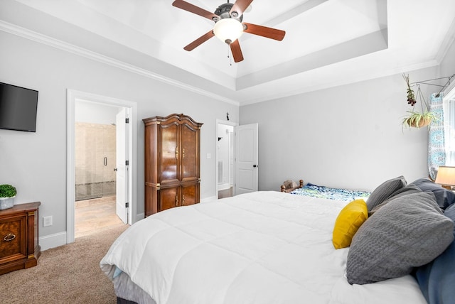 bedroom featuring connected bathroom, light carpet, a ceiling fan, ornamental molding, and a tray ceiling