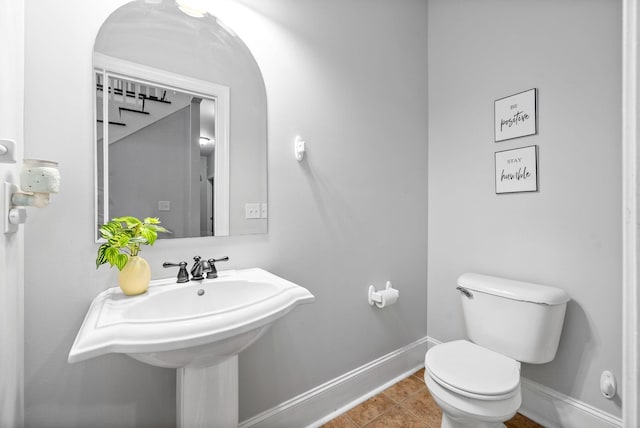 half bath with tile patterned floors, toilet, and baseboards