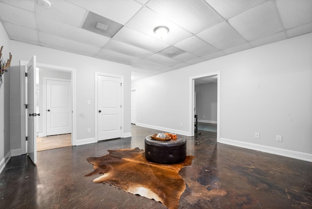 unfurnished room featuring finished concrete floors, a drop ceiling, and baseboards