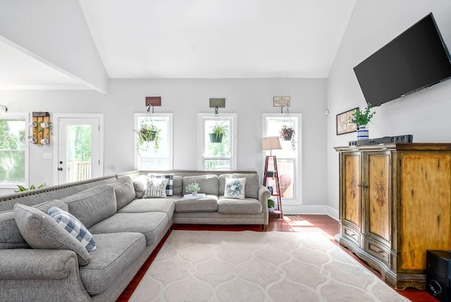 living area featuring lofted ceiling, wood finished floors, and baseboards