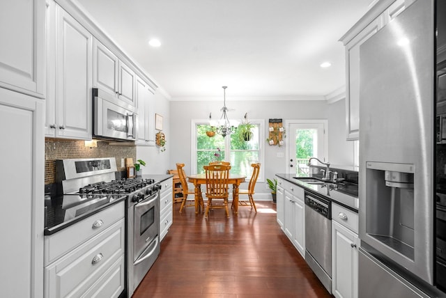 kitchen with appliances with stainless steel finishes, dark countertops, crown molding, and a sink