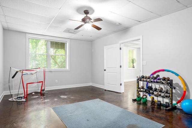 workout room featuring a paneled ceiling and baseboards