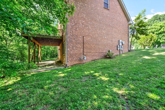 view of side of property with a deck, a lawn, and brick siding