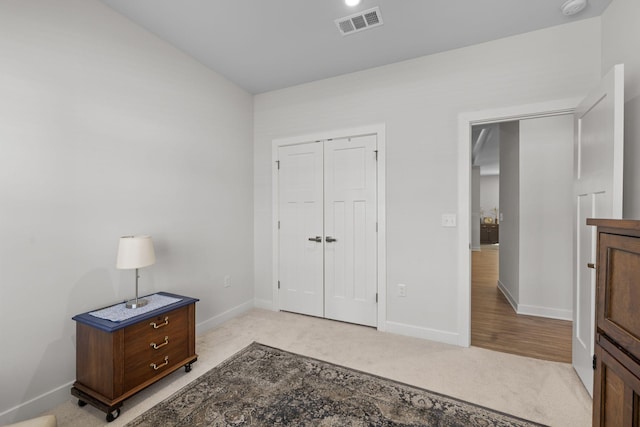 bedroom featuring baseboards, visible vents, a closet, and light colored carpet