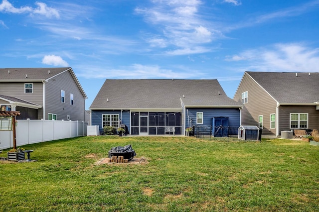 rear view of property featuring an outdoor fire pit, a sunroom, fence, cooling unit, and a yard