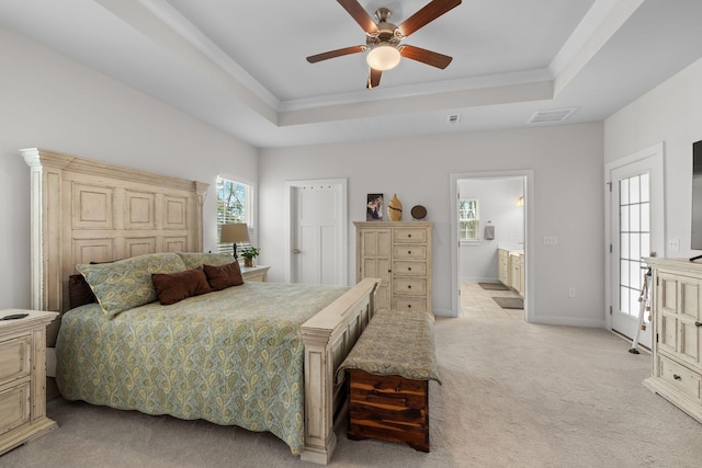 bedroom with a tray ceiling, visible vents, light carpet, and baseboards