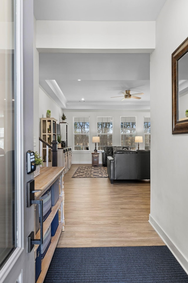 living area with ceiling fan, ornamental molding, wood finished floors, and baseboards