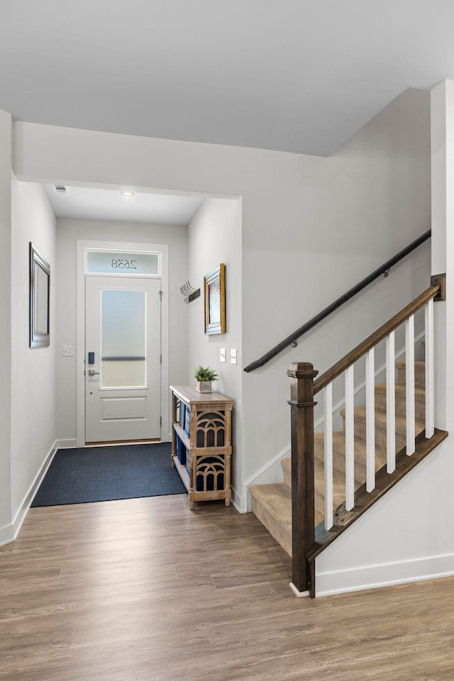 entryway featuring baseboards, stairway, and wood finished floors