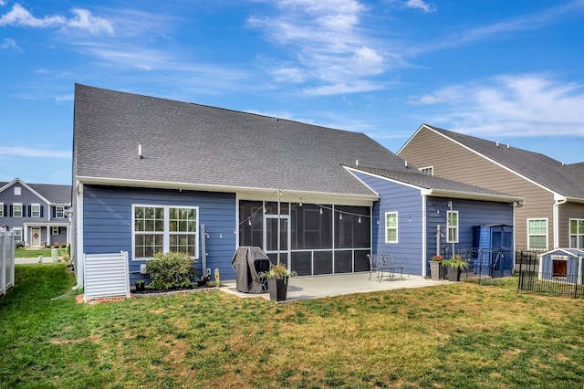 rear view of house featuring a patio, a shingled roof, fence, a sunroom, and a yard